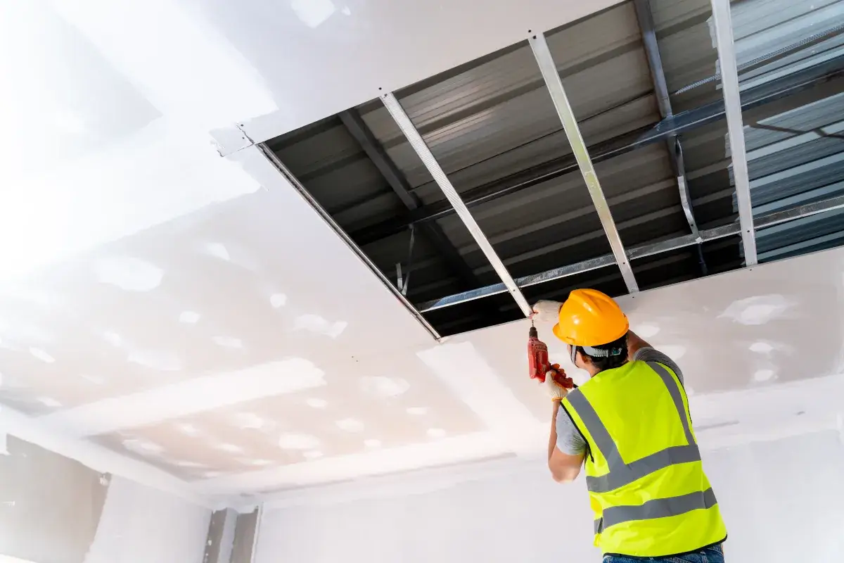 Profissional instalando a estrutura metálica de um forro de drywall